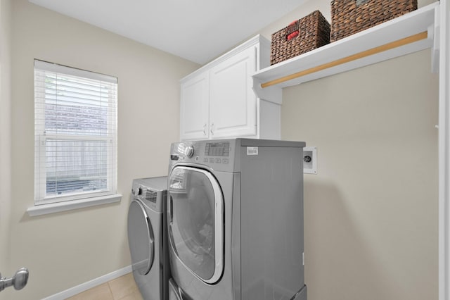 laundry room with cabinet space, light tile patterned floors, washing machine and dryer, and baseboards