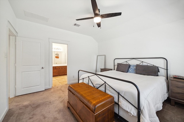 bedroom featuring visible vents, ceiling fan, vaulted ceiling, ensuite bathroom, and light colored carpet