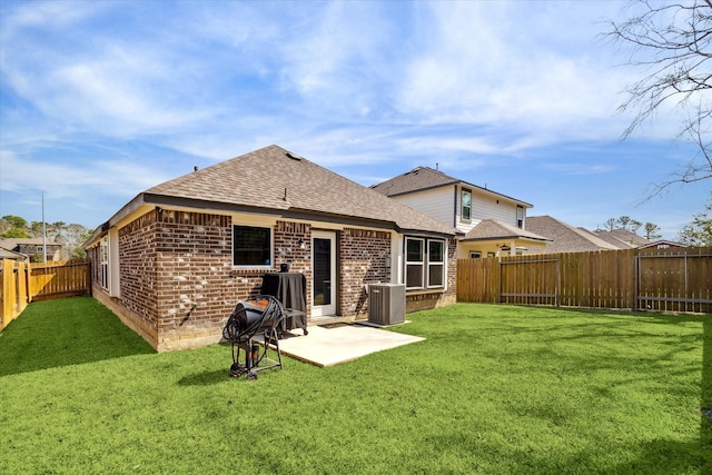 back of property featuring brick siding, a fenced backyard, a lawn, and central AC