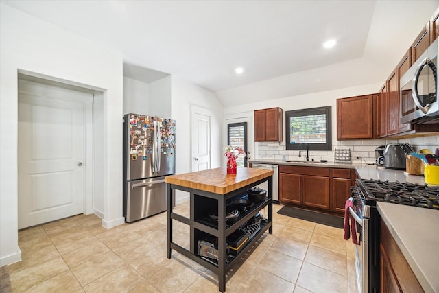 kitchen with a sink, stainless steel appliances, light countertops, light tile patterned floors, and decorative backsplash