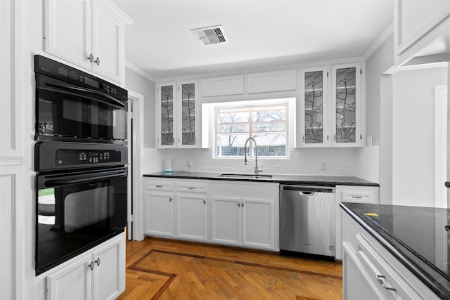 kitchen featuring visible vents, dobule oven black, a sink, decorative backsplash, and dishwasher