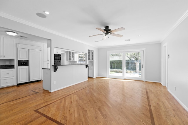 unfurnished living room featuring baseboards, visible vents, light wood finished floors, ceiling fan, and crown molding