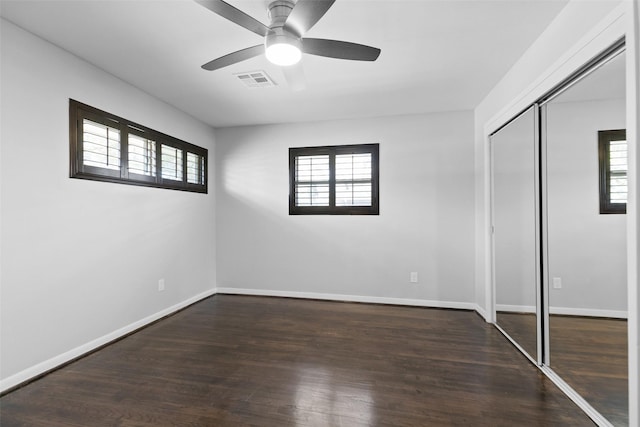 unfurnished bedroom with wood finished floors, visible vents, a closet, and baseboards