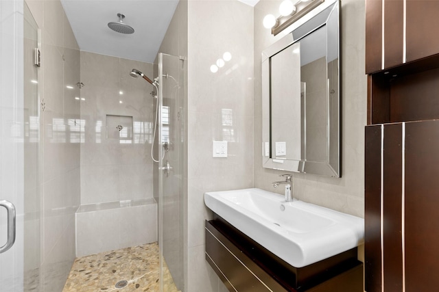 full bathroom with vanity, a shower stall, and tile walls