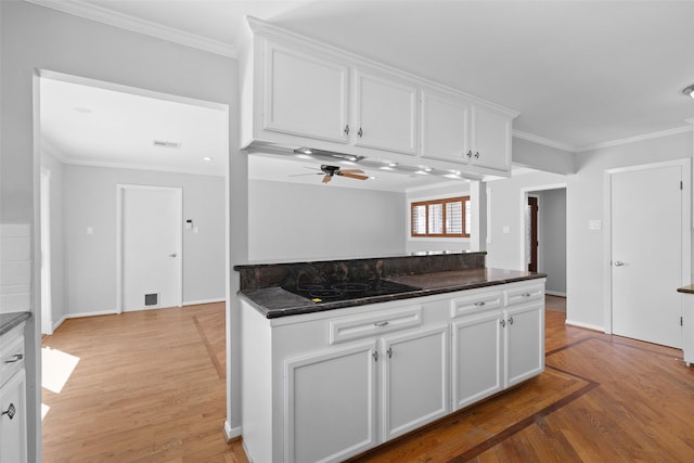 kitchen with white cabinetry, black electric stovetop, light wood-type flooring, and ornamental molding