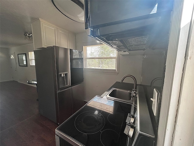 kitchen featuring a sink, range with electric cooktop, refrigerator with ice dispenser, and white cabinetry