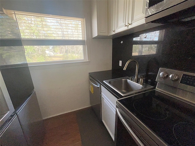 kitchen featuring a sink, stainless steel appliances, dark countertops, and white cabinetry