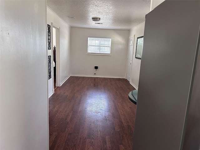 empty room featuring wood finished floors, baseboards, visible vents, ornamental molding, and a textured ceiling