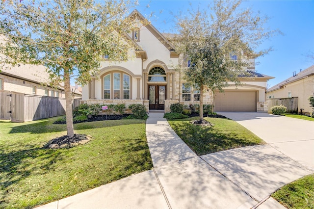 view of front facade with fence, driveway, an attached garage, stucco siding, and french doors