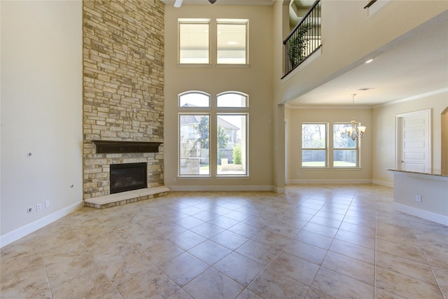 unfurnished living room with baseboards, an inviting chandelier, ornamental molding, and a fireplace