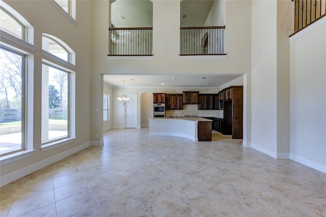 unfurnished living room featuring a chandelier and baseboards