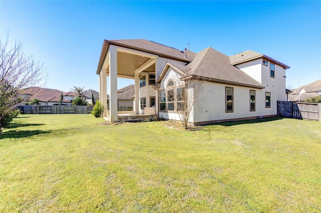 back of house featuring stucco siding, a yard, a fenced backyard, and a shingled roof