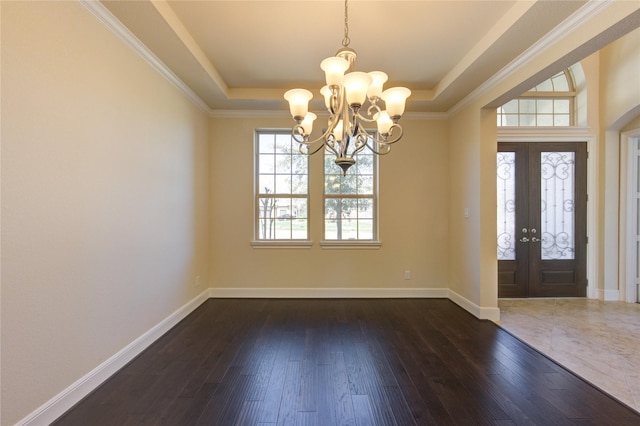 foyer entrance with an inviting chandelier, a tray ceiling, and dark wood-style flooring