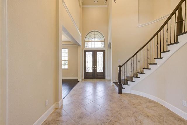 foyer entrance featuring stairway, baseboards, and a high ceiling