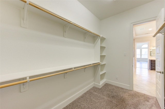 spacious closet with light tile patterned floors and light colored carpet