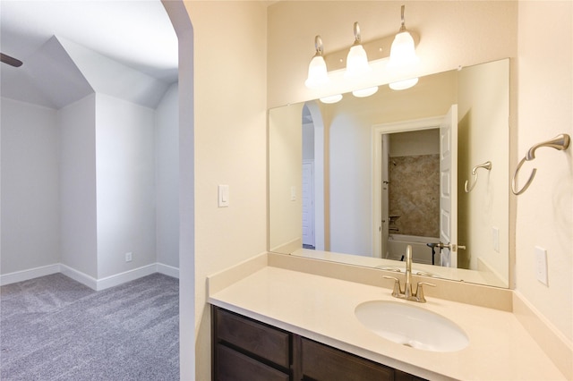 bathroom with baseboards, vanity, and lofted ceiling