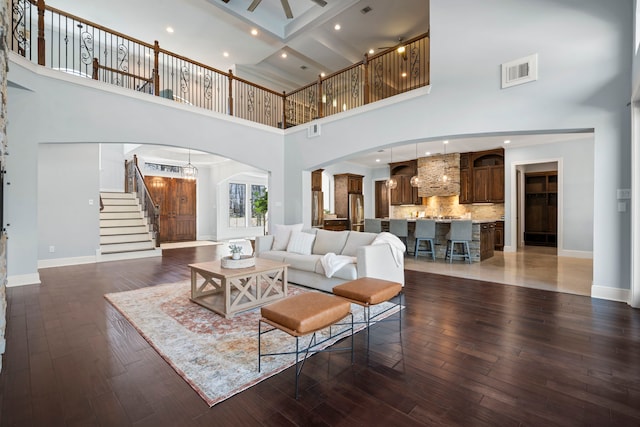 living room featuring visible vents, arched walkways, wood finished floors, and stairs