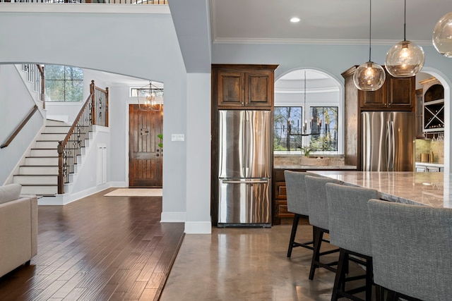 kitchen featuring a chandelier, arched walkways, freestanding refrigerator, and light stone countertops