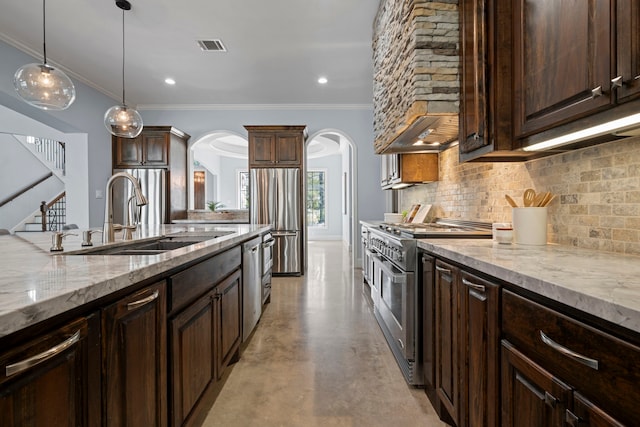 kitchen with tasteful backsplash, dark brown cabinets, arched walkways, stainless steel appliances, and a sink