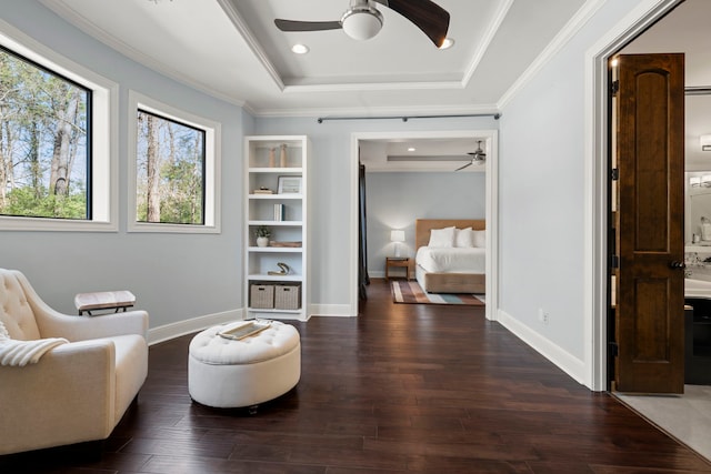 sitting room with a tray ceiling, a ceiling fan, and wood finished floors