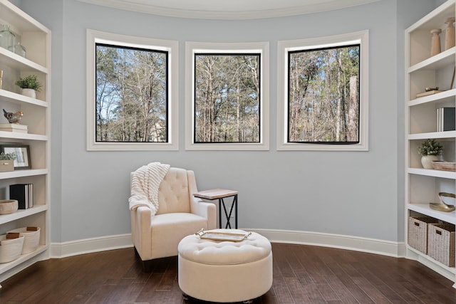 sitting room with dark wood-style floors, a healthy amount of sunlight, built in shelves, and baseboards