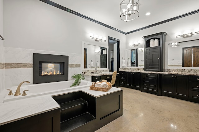 full bathroom featuring a notable chandelier, two vanities, ornamental molding, a sink, and a bathtub