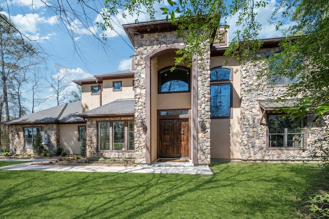 view of front of house with a front lawn, stone siding, and stucco siding