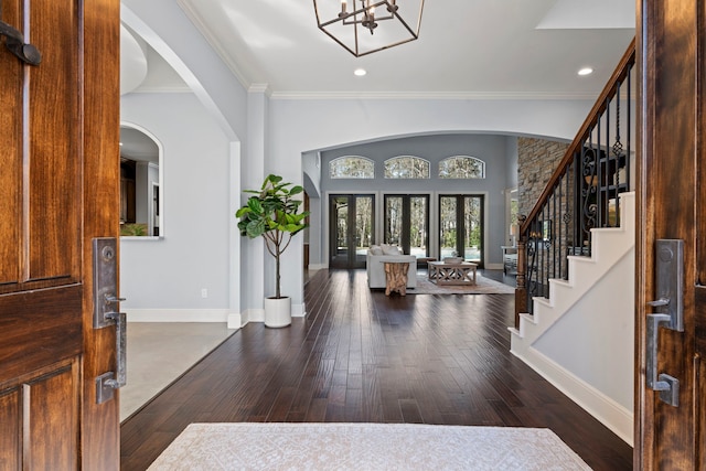 foyer featuring stairway, a notable chandelier, baseboards, and wood-type flooring