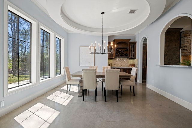 dining room featuring visible vents, finished concrete floors, baseboards, an inviting chandelier, and a raised ceiling