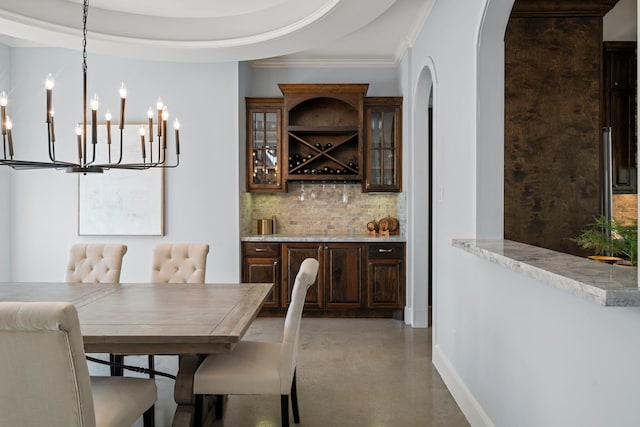 dining room featuring baseboards, concrete flooring, ornamental molding, arched walkways, and a notable chandelier