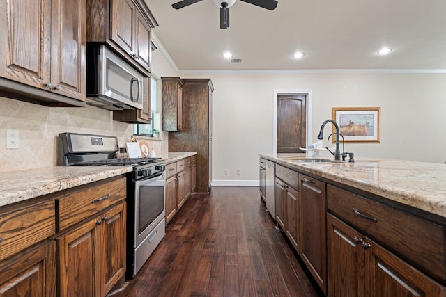 kitchen with appliances with stainless steel finishes, light stone countertops, crown molding, and a sink