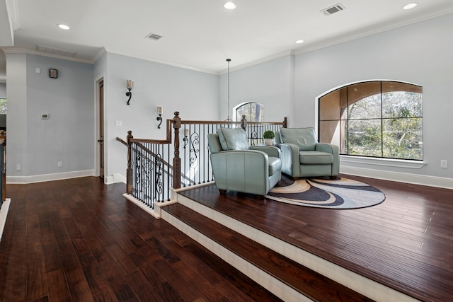 living area featuring visible vents, an upstairs landing, wood-type flooring, crown molding, and baseboards