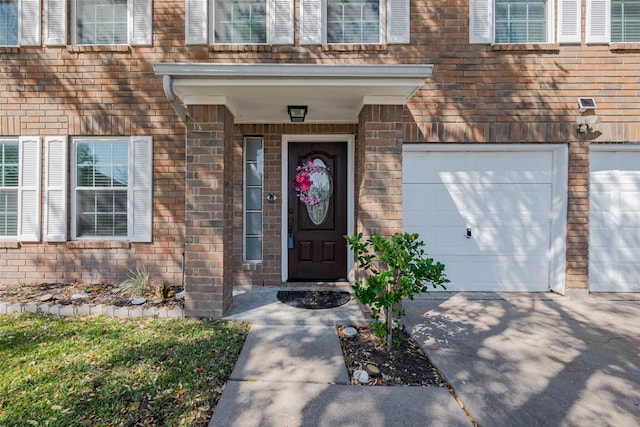 view of exterior entry featuring a garage, brick siding, and concrete driveway