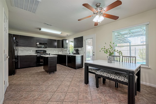 kitchen featuring black appliances, visible vents, dark cabinets, and a kitchen island