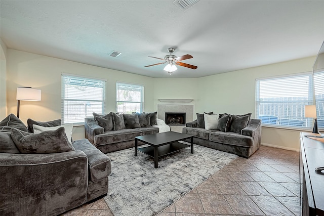 living area featuring baseboards, a ceiling fan, visible vents, and a tile fireplace