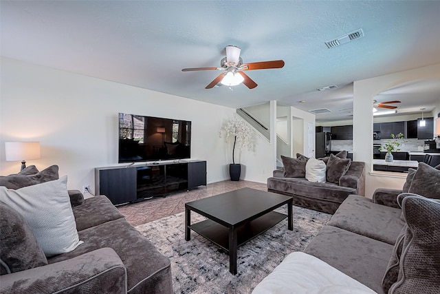 living room featuring visible vents, a textured ceiling, and ceiling fan