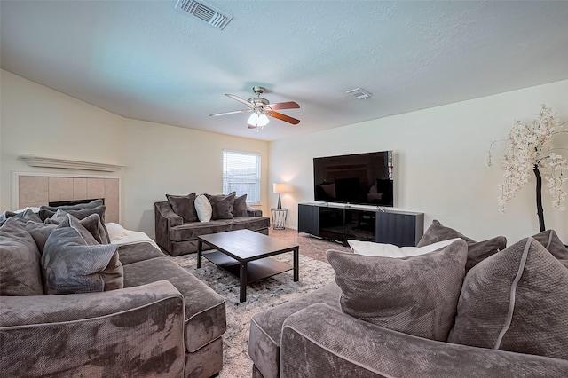 living room with visible vents, a textured ceiling, and ceiling fan