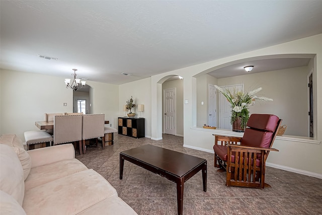 living room with a notable chandelier, arched walkways, visible vents, and baseboards