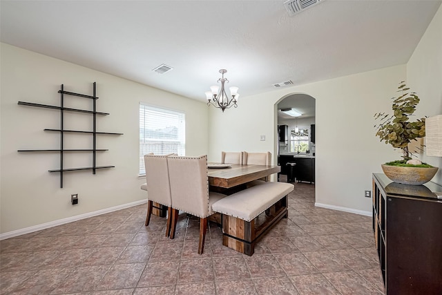 dining room featuring visible vents, arched walkways, baseboards, and a chandelier