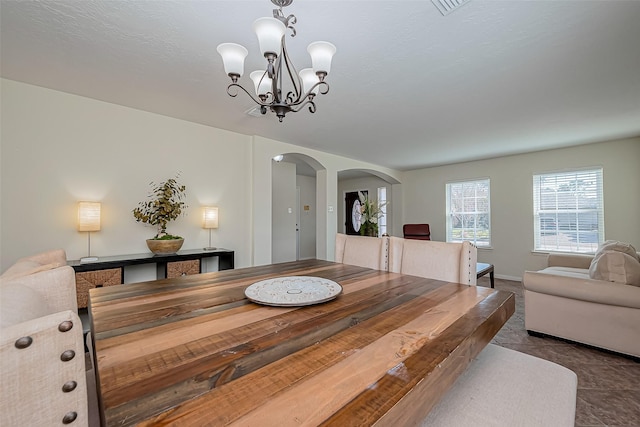 dining room with an inviting chandelier, baseboards, and arched walkways