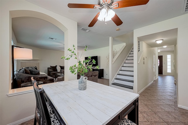 dining room featuring visible vents, baseboards, ceiling fan, and stairs