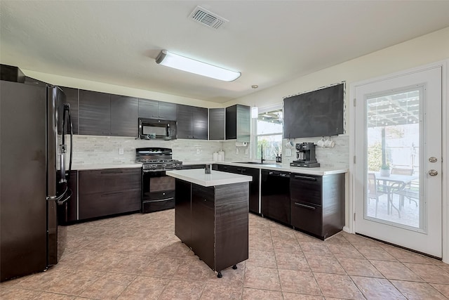 kitchen with visible vents, backsplash, light countertops, black appliances, and a sink