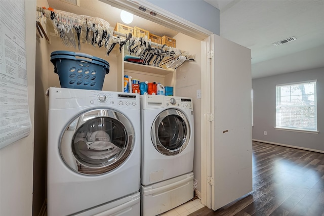 clothes washing area featuring wood finished floors, baseboards, visible vents, washing machine and clothes dryer, and laundry area