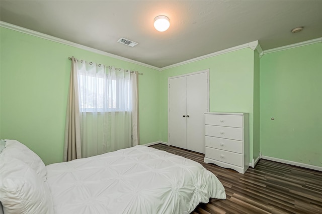 bedroom with visible vents, crown molding, baseboards, wood finished floors, and a closet