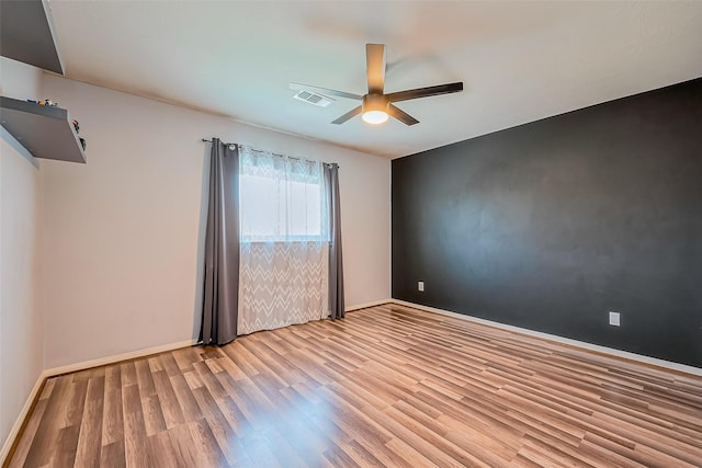 empty room featuring a ceiling fan, light wood-style floors, and baseboards