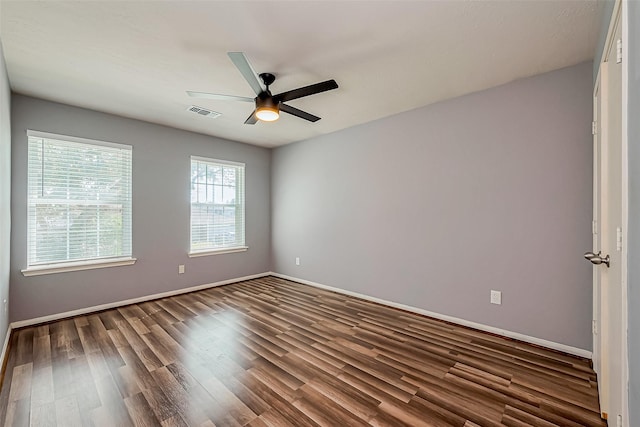 unfurnished room with visible vents, baseboards, dark wood-type flooring, and a ceiling fan