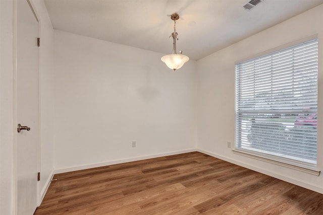 unfurnished room featuring wood finished floors, visible vents, and baseboards