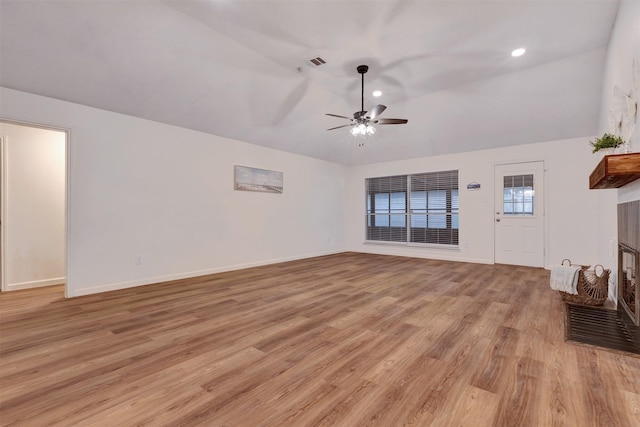 unfurnished living room with visible vents, a ceiling fan, light wood-style floors, baseboards, and vaulted ceiling