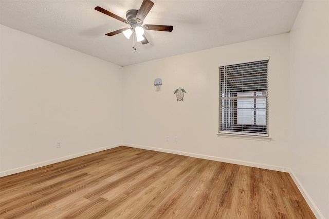 spare room featuring a ceiling fan, baseboards, and light wood finished floors