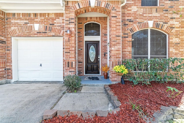 entrance to property featuring brick siding, driveway, and a garage